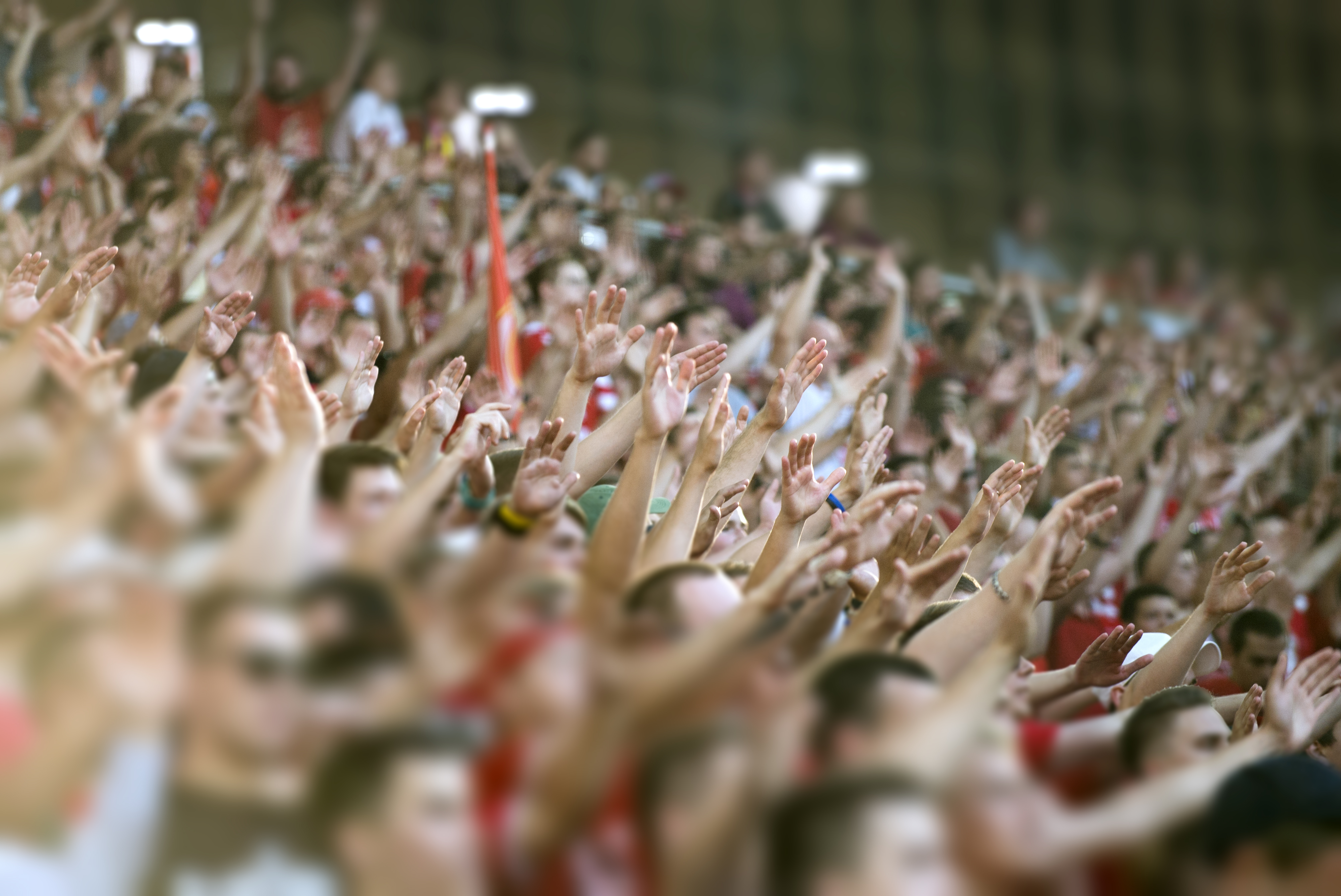 Close-up of crowd at cricket match with arms up