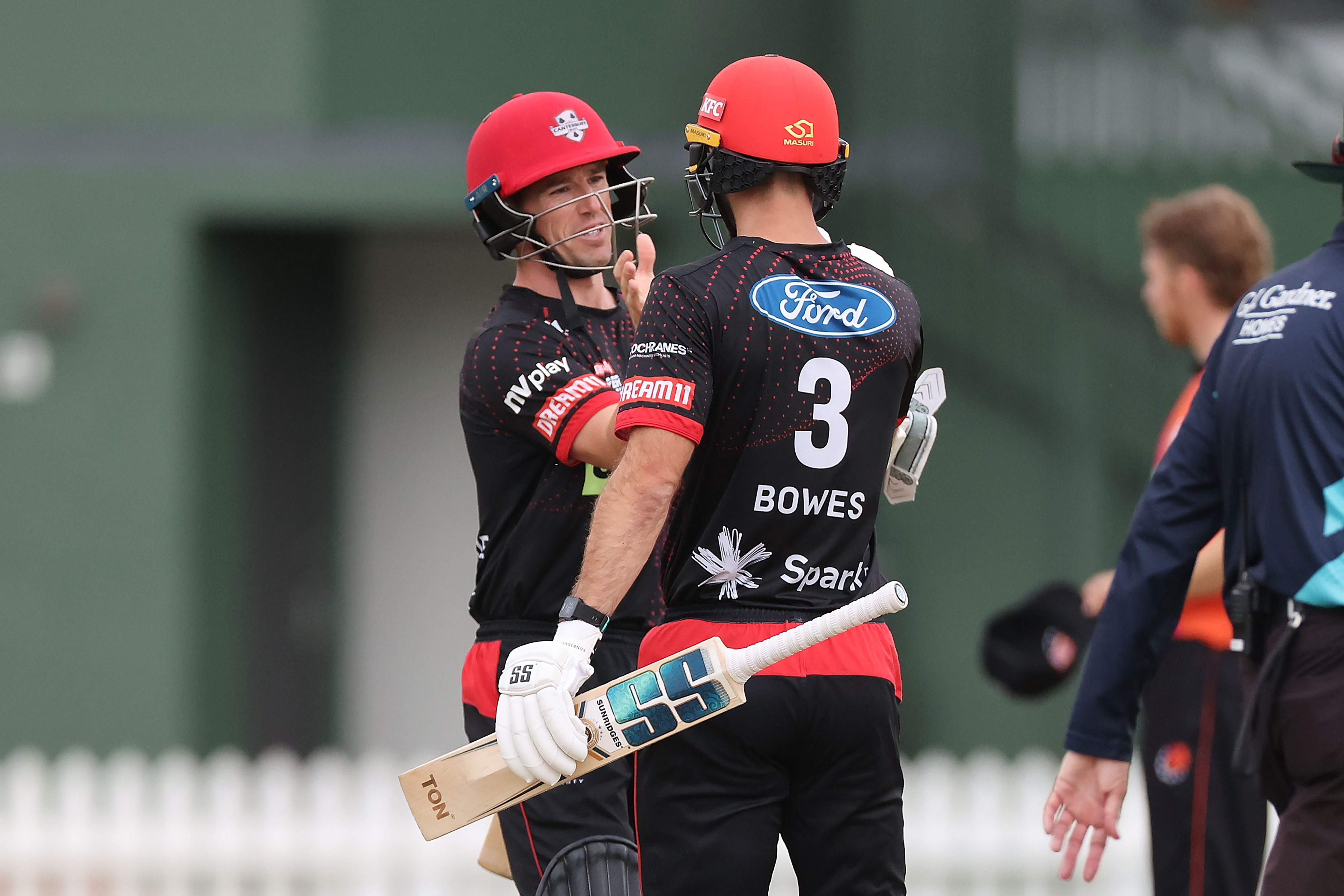 Two Canterbury Cricket players about to shake hands with NV Play logo on arm