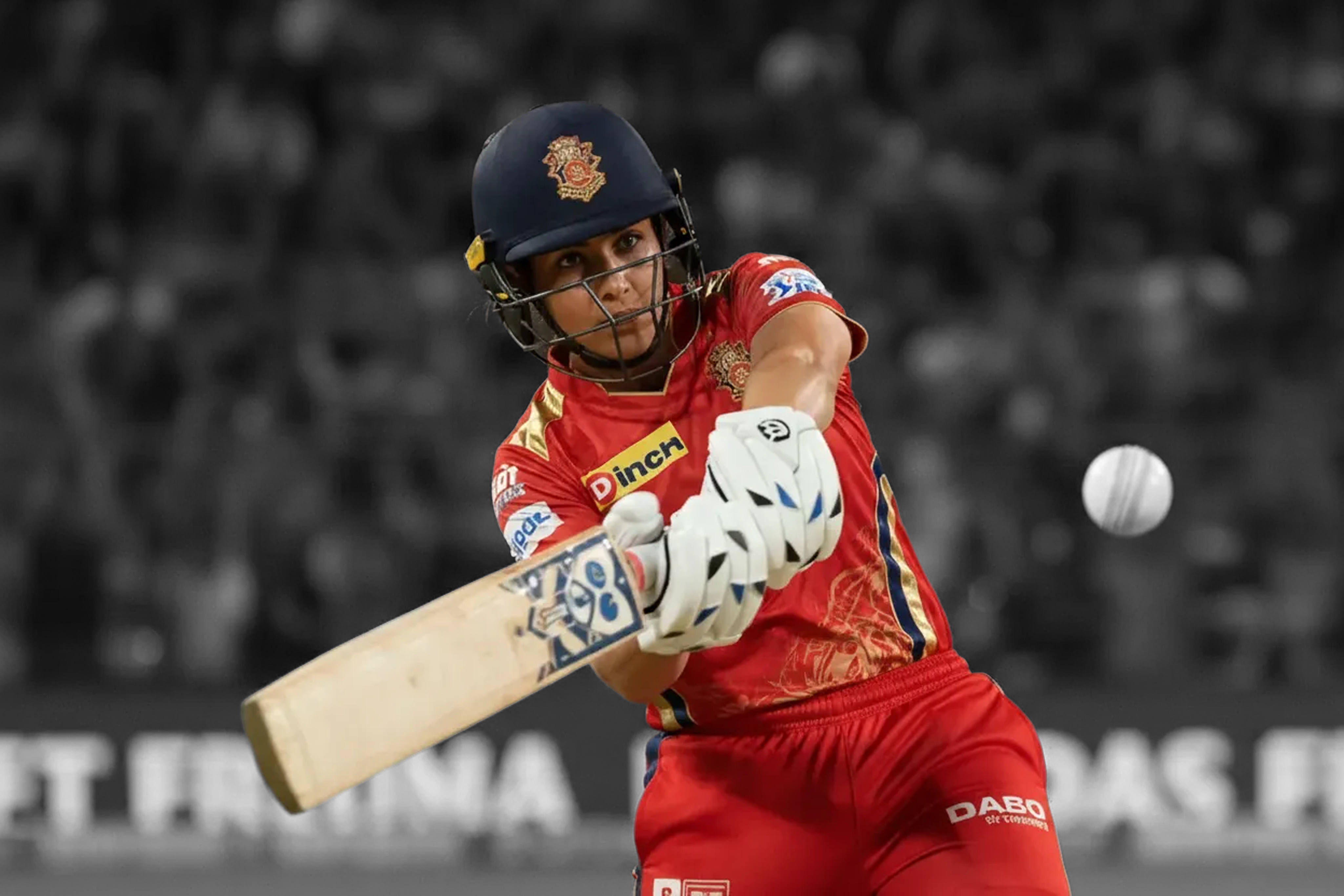 Female pro cricketer in red hitting a cricket ball in a crowded stadium
