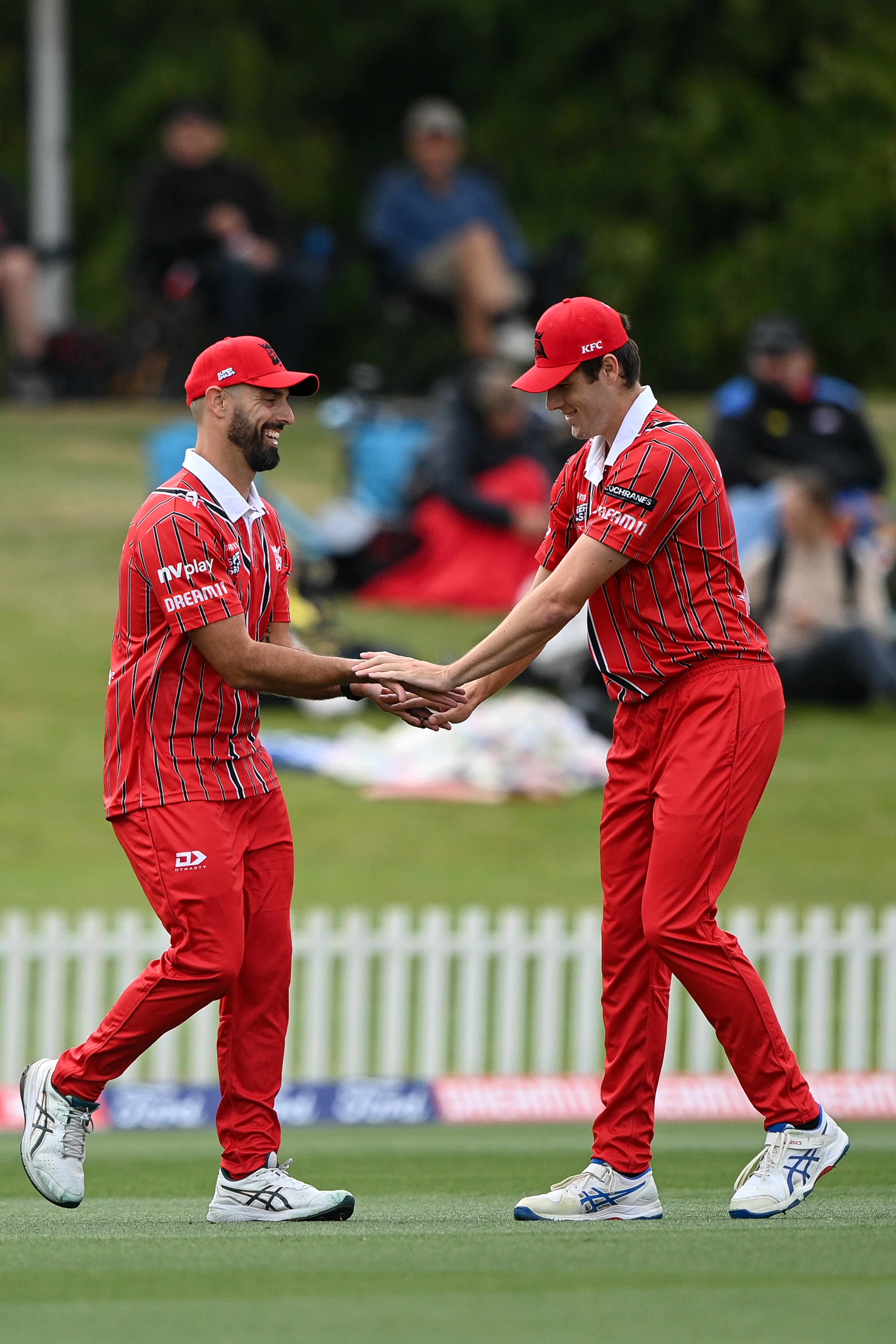 Two Canterbury Club Cricket players low-fiving at a cricket match